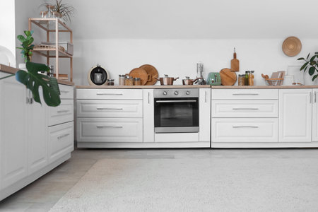 Interior of kitchen with white counters, shelf unit and utensils