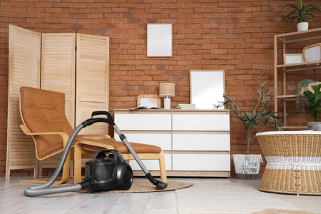 Interior of living room with vacuum cleaner, armchair and drawersの写真素材