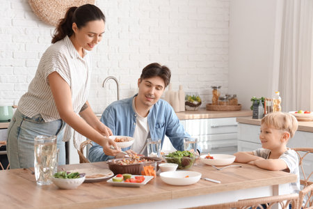 Young woman putting Fajita on plate at dinner with her family in kitchenの写真素材