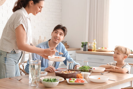 Young woman putting Fajita on plate at dinner with her family in kitchenの写真素材
