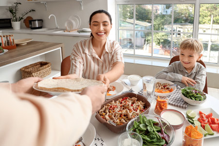 Young woman taking tortillas for Fajita from her husband at family dinner in kitchenの写真素材