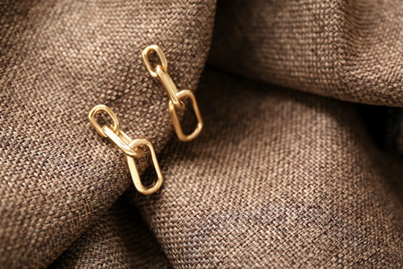 Beautiful golden earrings on fabric background, closeupの写真素材