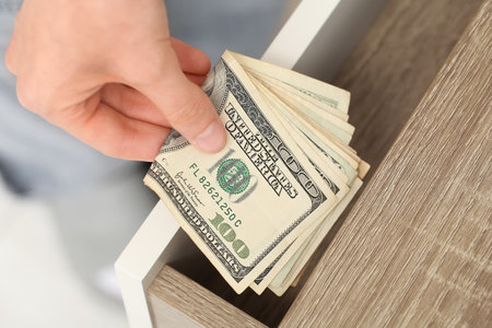 Woman hiding dollar banknotes in drawer at home, closeupの写真素材