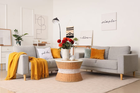 Interior of stylish living room with gray sofas, beautiful dahlia flowers and cup of tea on coffee...