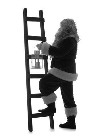 Silhouette of Santa Claus with lantern climbing ladder on white backgroundの写真素材