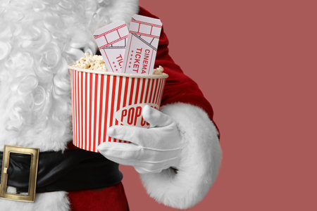 Santa Claus with bucket of popcorn and cinema tickets on pink background. Closeupの写真素材