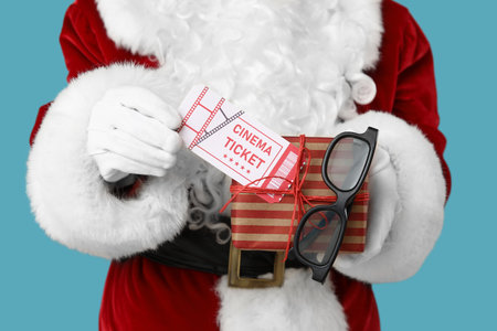 Santa Claus with gift box, cinema tickets and 3D glasses on blue background. Closeupの写真素材