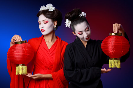 Beautiful young geishas with lanterns on color backgroundの写真素材