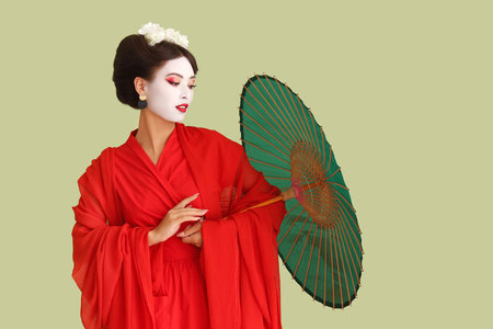 Beautiful young geisha with parasol on green backgroundの写真素材