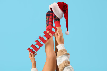 Legs of young woman with the word HOHOHO and Santa hat on blue backgroundの写真素材