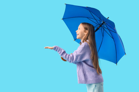 Cute teenage girl with blue umbrella on color backgroundの写真素材