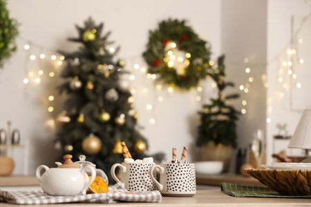 Interior of stylish decorated kitchen with Christmas mistletoe wreath on white wall and cups of cocoa drink on tableの写真素材