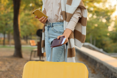 Woman with suitcase and passport in autumn park, closeupの写真素材