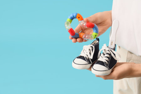 Woman with pregnancy test, baby boots and rattle on blue background. Closeup