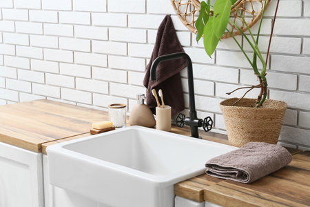 Sink with bath accessories near white brick wall in bathroomの写真素材