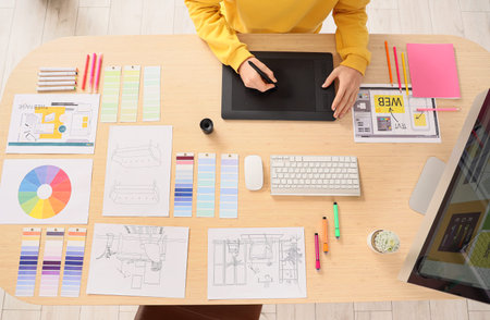 Male graphic designer with tablet working at table in office, top view