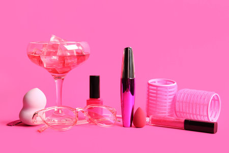 Composition with decorative cosmetics, accessories and glass of cocktail on pink backgroundの写真素材