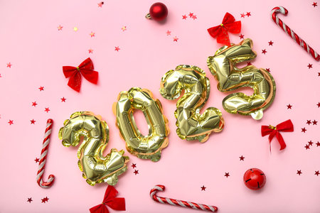 Figure 2025 made of foil balloons with Christmas balls, bows and candy canes on pink backgroundの写真素材