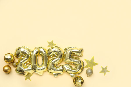 Figure 2025 made of foil balloons with Christmas balls and stars on yellow backgroundの写真素材