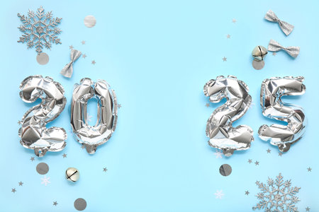 Figure 2025 made of foil balloons with Christmas decorations and confetti on blue background