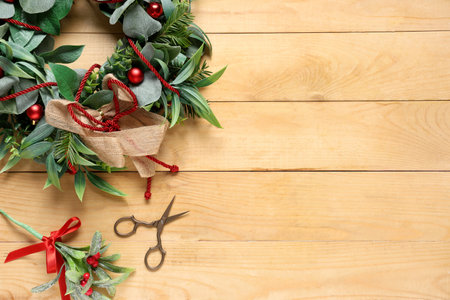 Beautiful Christmas mistletoe wreath with supplies on beige wooden backgroundの写真素材