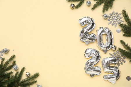 Figure 2025 made of foil balloons with Christmas balls, snowflakes and fir branches on yellow...