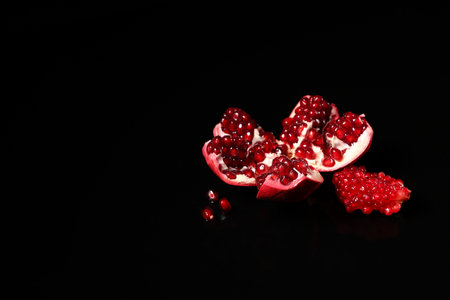 Pieces of tasty ripe pomegranate on black backgroundの写真素材