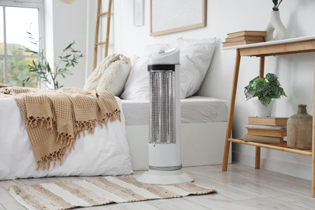 Electric heater on rug in bedroom interiorの写真素材