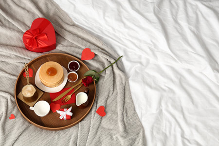 Tray with breakfast, rose and gifts for Valentine's Day on bed, top viewの写真素材