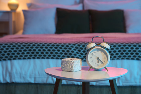 Retro alarm clock with candle on table in dark bedroom at night, closeupの写真素材