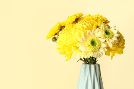 Vase with beautiful chrysanthemum flowers on yellow backgroundの写真素材