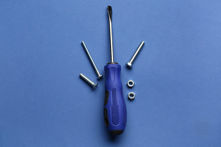Composition with screwdriver, tap bolts and nuts on blue background