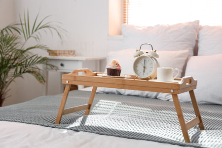 Tray with breakfast and alarm clock in bedroom