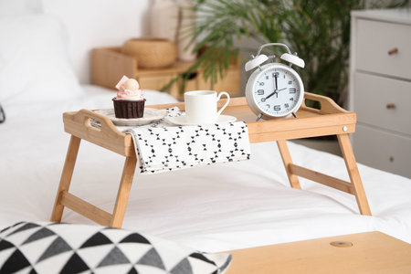 Tray with breakfast and retro alarm clock in bedroom