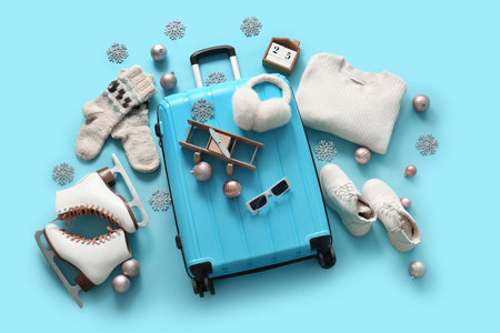 Suitcase with winter clothes and Christmas decor on blue background. Top viewの写真素材
