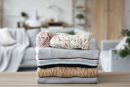 Stack of folded winter clothes with hat on table in room, closeupの写真素材