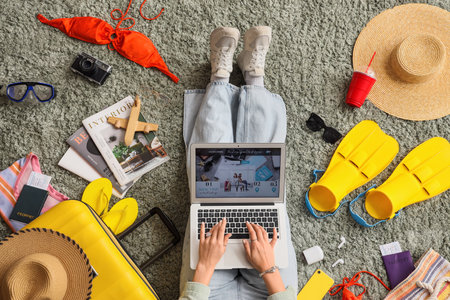 Female travel blogger using laptop with beach accessories on green carpet, top viewの写真素材