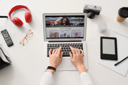 Female blogger using laptop with modern gadgets on white table, top viewの写真素材