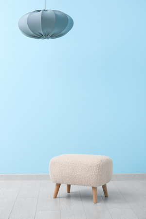 White pouf and hanging lamp near blue wall in roomの写真素材