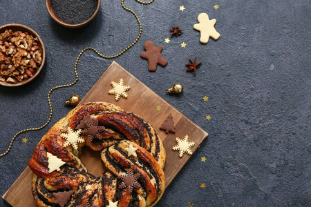 Composition with tasty Christmas pastry wreath, poppy seeds, walnuts and decor on dark backgroundの写真素材