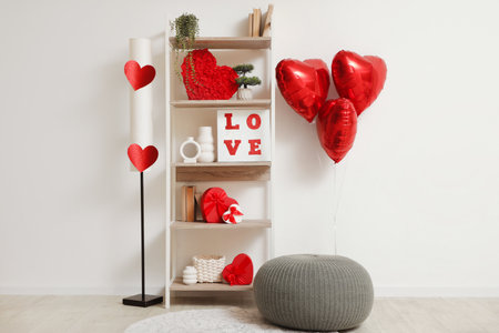 Interior of light room decorated for Valentine's Day with shelf unit, lamp and poufの写真素材