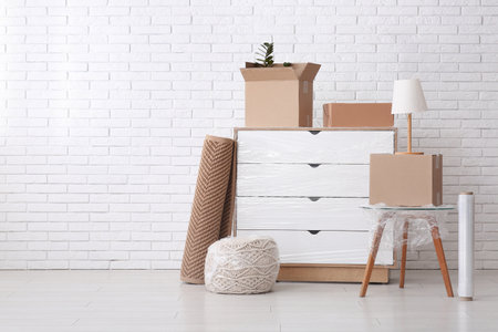 Commode, table and cardboard boxes with stretch film in room on moving dayの写真素材