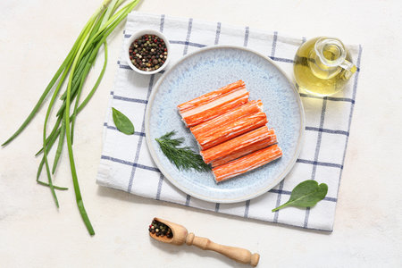 Plate with tasty crab sticks, dill and bowl of peppercorns on white backgroundの写真素材