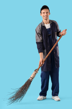 Male scavenger with broom sweeping on blue backgroundの写真素材