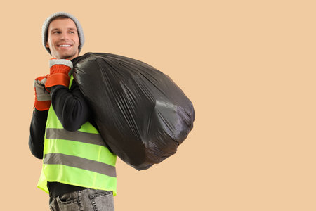 Male scavenger with full garbage bag on beige backgroundの写真素材