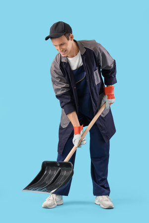 Male scavenger with snow shovel on blue backgroundの写真素材