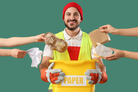 Male scavenger holding trash bin and female hands with paper garbage on green backgroundの写真素材