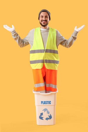 Male scavenger in recycle trash bin for plastic on yellow backgroundの写真素材