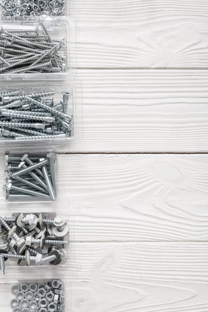 Packages with tap bolts, screws and chrome nuts on white wooden backgroundの写真素材