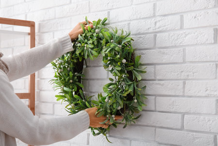 Woman Christmas mistletoe wreath on white brick wallの写真素材
